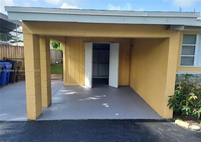 doorway to property with stucco siding and fence