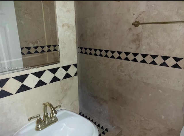 full bathroom featuring tiled shower and a sink