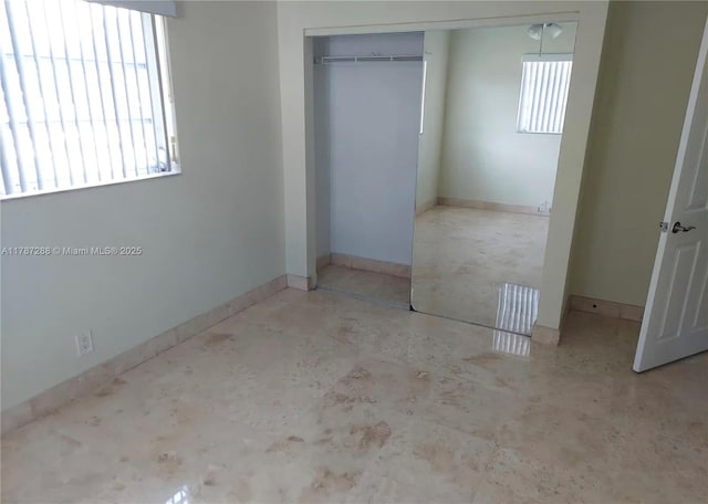unfurnished bedroom with baseboards and a closet