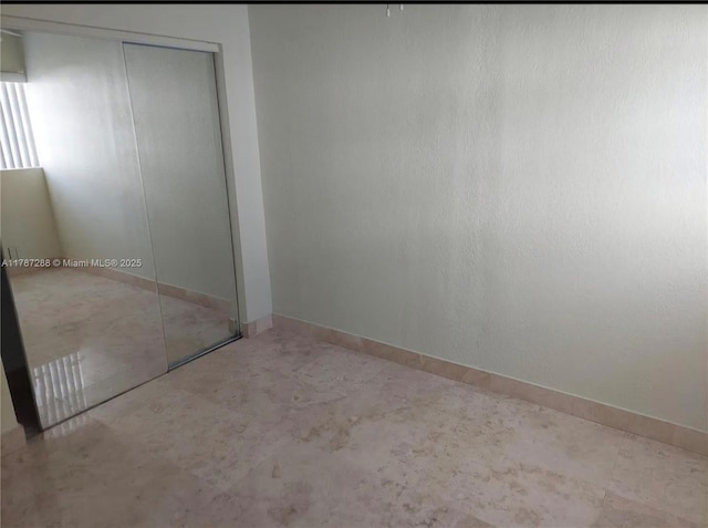 unfurnished bedroom with a closet and baseboards