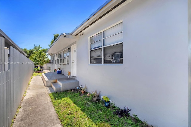 view of side of home featuring stucco siding and fence