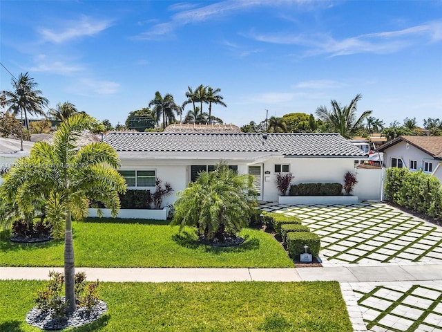 view of front of house with a tile roof, a front lawn, stucco siding, and driveway