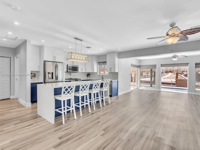 kitchen featuring recessed lighting, a kitchen breakfast bar, light wood-style floors, baseboards, and appliances with stainless steel finishes