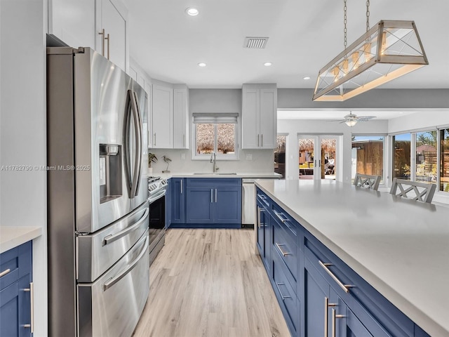 kitchen featuring plenty of natural light, stainless steel appliances, visible vents, a sink, and blue cabinetry