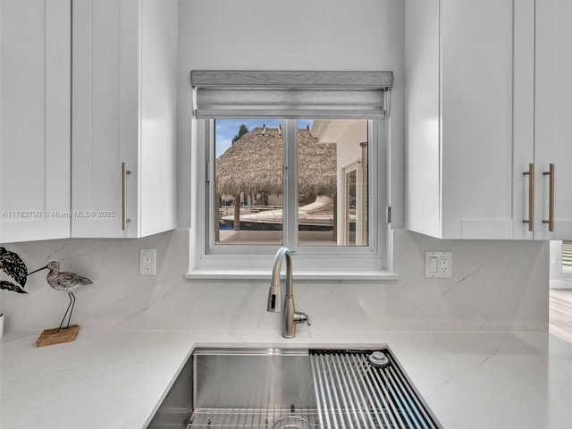 kitchen with decorative backsplash, white cabinetry, and light stone counters