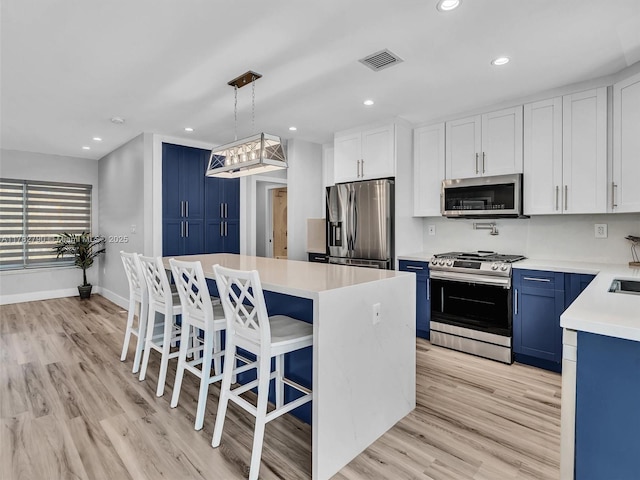 kitchen with stainless steel appliances, light countertops, visible vents, a center island, and blue cabinetry
