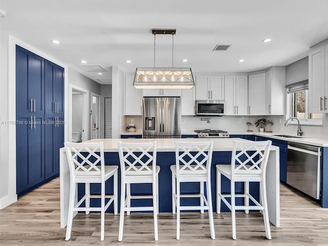 kitchen featuring a sink, stainless steel appliances, light countertops, blue cabinetry, and visible vents