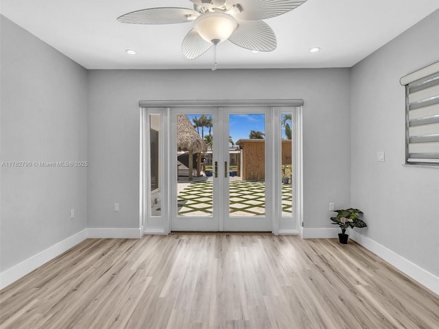 spare room featuring wood finished floors, baseboards, ceiling fan, and french doors
