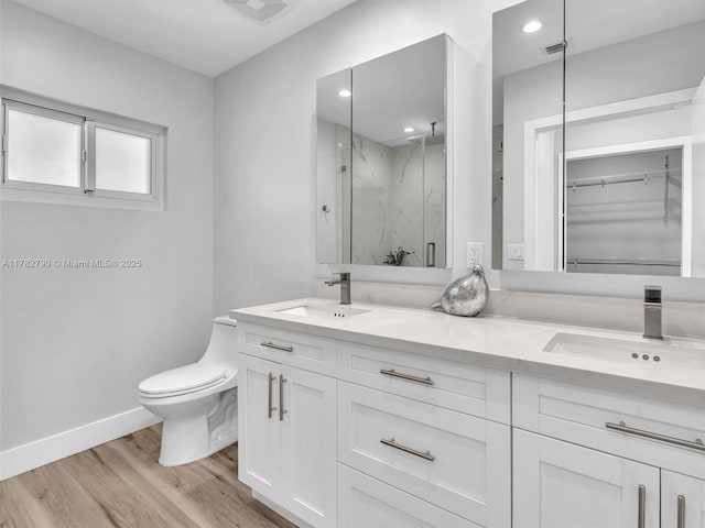 full bath with toilet, wood finished floors, a sink, and a marble finish shower