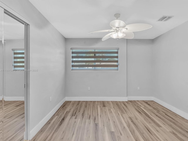 spare room with wood finished floors, visible vents, baseboards, and ceiling fan