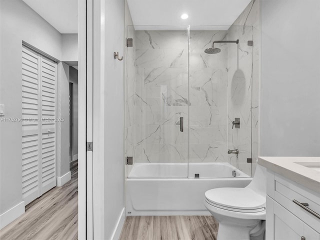 full bath with toilet, wood finished floors, vanity, baseboards, and bathing tub / shower combination