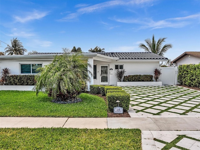 view of front of home featuring a tile roof, a front yard, and stucco siding