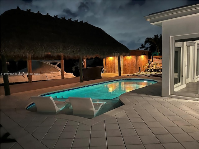 pool at night featuring a patio area, a fenced backyard, and an outdoor pool