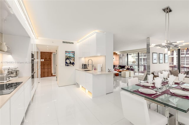 10205 Collins Ave Unit 1106, Bal Harbour, FL 33154 - kitchen with black electric stovetop, modern cabinets, a sink, and white cabinetry