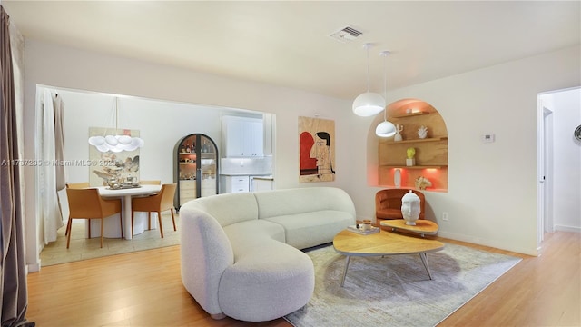 living room featuring light wood-type flooring, visible vents, and baseboards