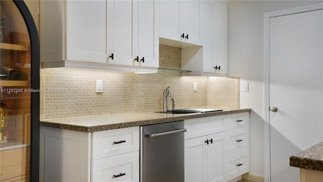 kitchen featuring stone counters, white cabinetry, decorative backsplash, and a sink