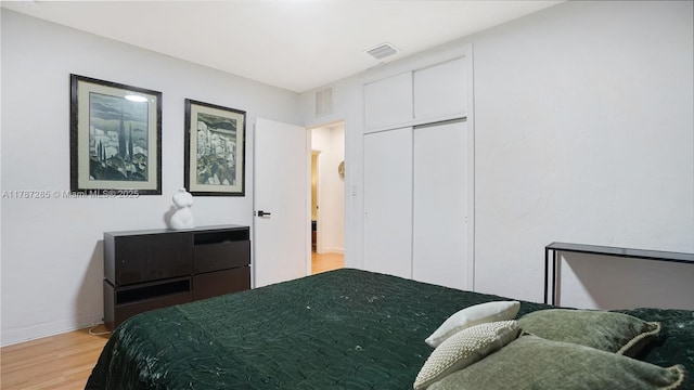 bedroom with baseboards, a closet, visible vents, and light wood-style flooring