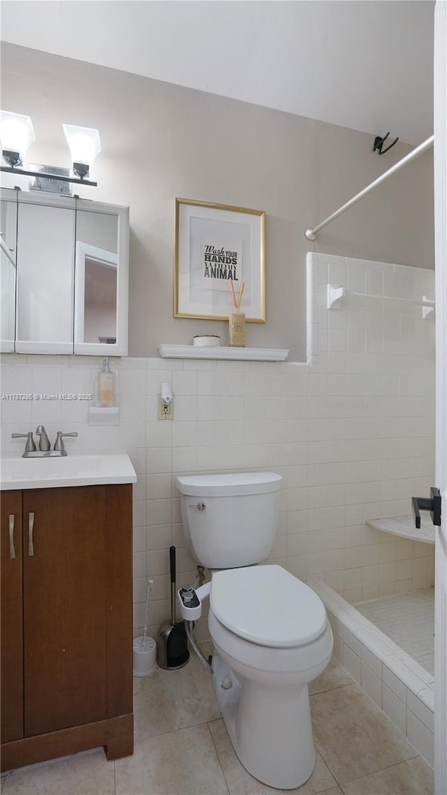 full bath featuring toilet, tile walls, tiled shower, tile patterned flooring, and vanity