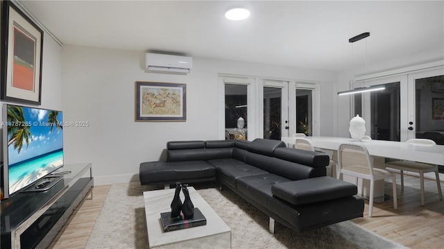living area featuring a wall mounted AC, light wood-type flooring, baseboards, and french doors