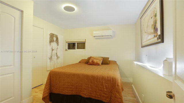 bedroom featuring light wood-style floors, baseboards, and a wall unit AC