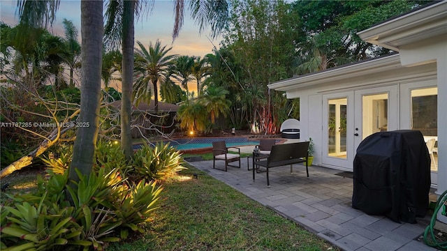 patio terrace at dusk with a grill and an outdoor pool