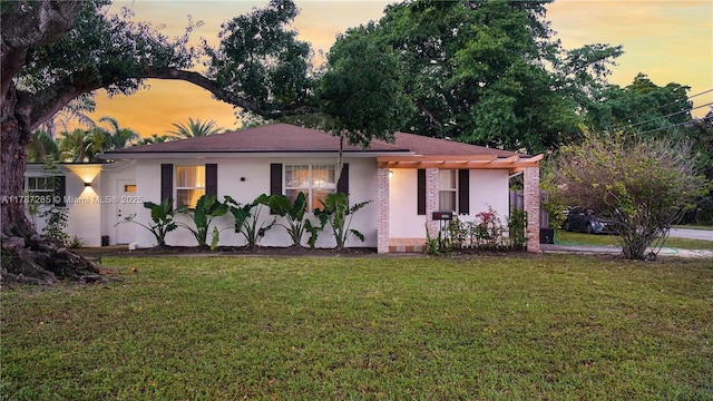 ranch-style home with a front yard and stucco siding