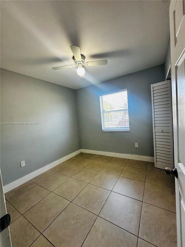 unfurnished bedroom with tile patterned floors, baseboards, and a ceiling fan