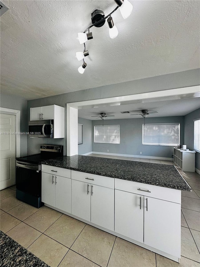 kitchen featuring white cabinets, stainless steel appliances, a ceiling fan, light tile patterned flooring, and a textured ceiling