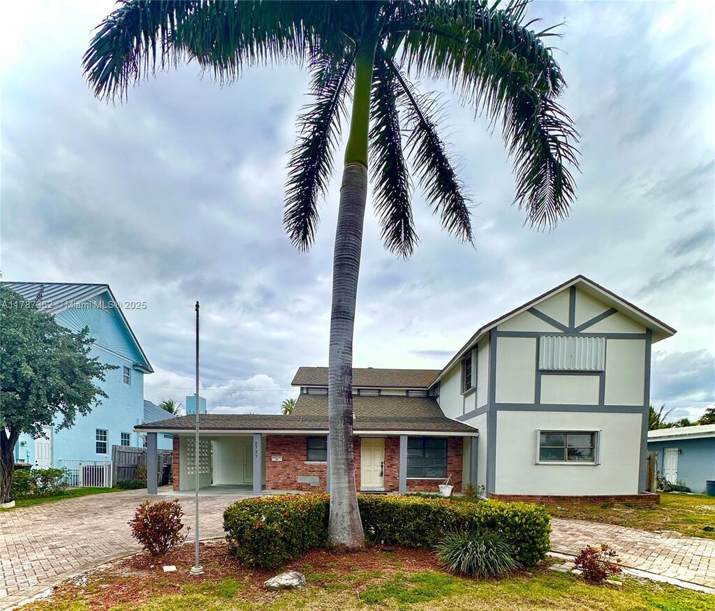 2727 NE 31st Ct, Lighthouse Point, FL 33064 - view of front of property with a carport, fence, brick siding, stucco siding, and decorative driveway