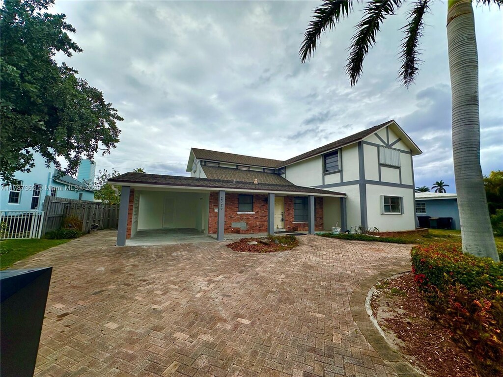 2727 NE 31st Ct, Lighthouse Point, FL 33064 - back of house with fence, an attached carport, and curved driveway