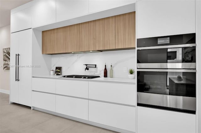 915 NE 17th Ter, Fort Lauderdale, FL 33304 - kitchen with white cabinetry, modern cabinets, light countertops, gas stovetop, and double oven