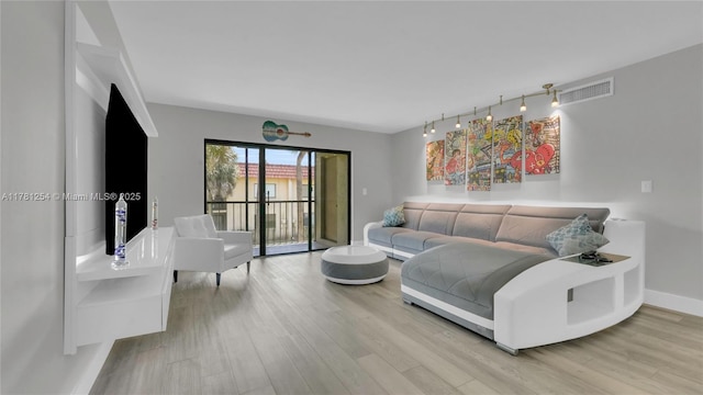 living room with track lighting, wood finished floors, visible vents, and baseboards