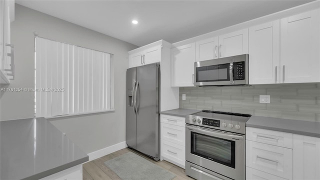 kitchen featuring recessed lighting, baseboards, decorative backsplash, appliances with stainless steel finishes, and white cabinetry