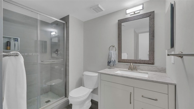 bathroom with toilet, vanity, visible vents, and a stall shower