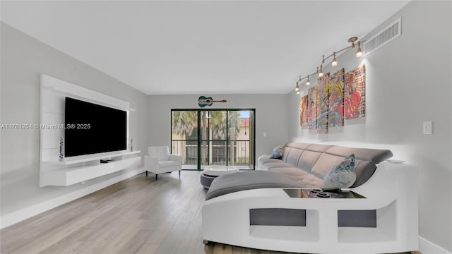 living room featuring track lighting, baseboards, wood finished floors, and visible vents