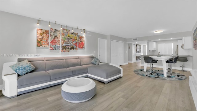 living room with visible vents, baseboards, and light wood-style floors
