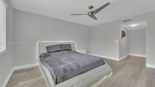 bedroom with visible vents, light wood finished floors, baseboards, and a ceiling fan
