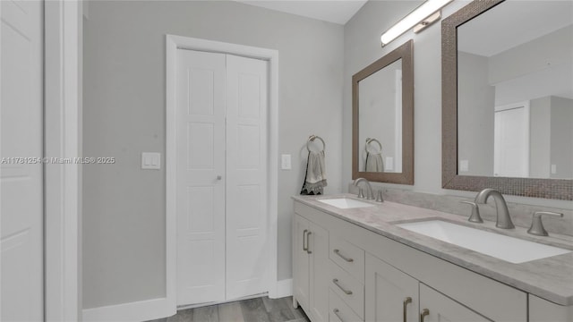 bathroom with baseboards, a sink, and double vanity