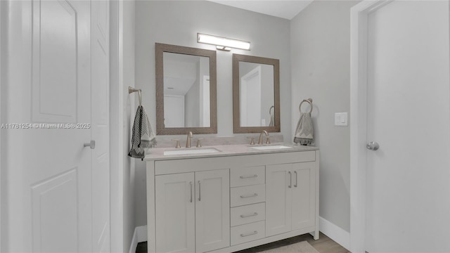 bathroom with baseboards, a sink, and double vanity