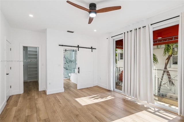 2905 Day Ave Unit 2A, Miami, FL 33133 - unfurnished bedroom featuring a barn door, a spacious closet, access to outside, light wood-style flooring, and baseboards