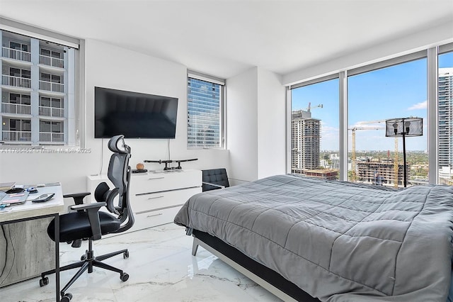 bedroom with marble tiled floors, multiple windows, and a desk