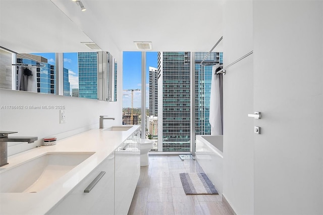 bathroom with floor to ceiling windows, a bathtub, double vanity, a shower, and toilet