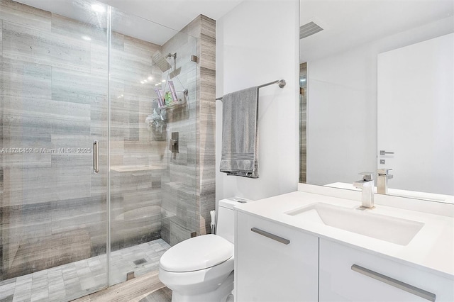 bathroom with toilet, a stall shower, and vanity