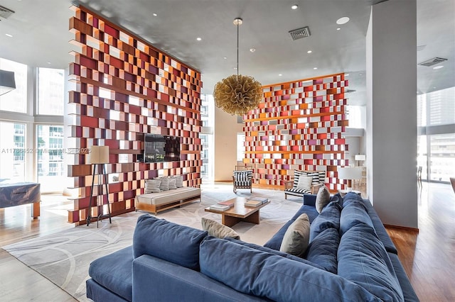 living area with floor to ceiling windows, healthy amount of natural light, wood finished floors, a towering ceiling, and recessed lighting