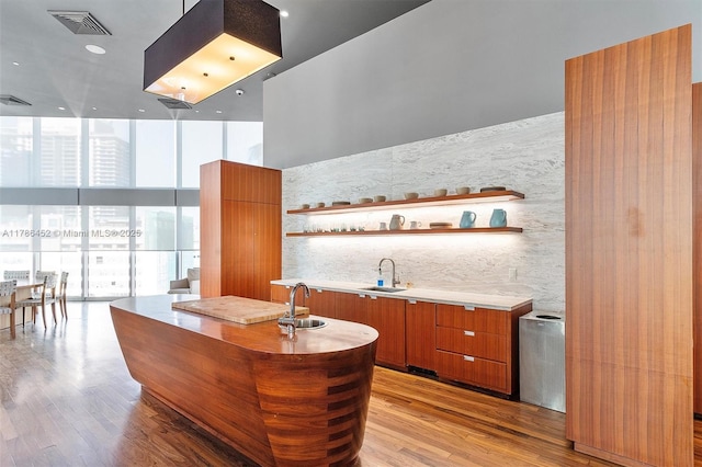 bar with a sink, floor to ceiling windows, and light wood-style flooring