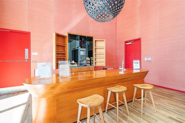indoor dry bar with a high ceiling, wood finished floors, and baseboards