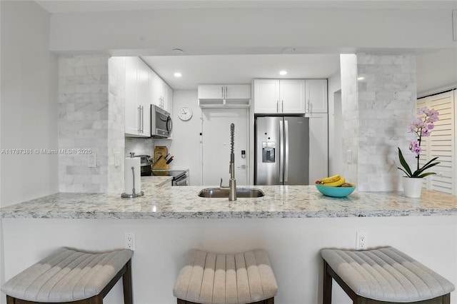 1831 NE 38th St Unit 402, Oakland Park, FL 33308 - kitchen featuring appliances with stainless steel finishes, a peninsula, white cabinetry, a sink, and recessed lighting