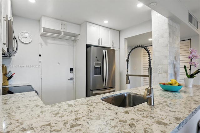 1831 NE 38th St Unit 402, Oakland Park, FL 33308 - kitchen with stainless steel fridge, light stone counters, a sink, white cabinetry, and ornate columns