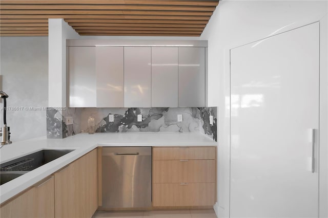 kitchen with modern cabinets, stainless steel dishwasher, light countertops, and backsplash