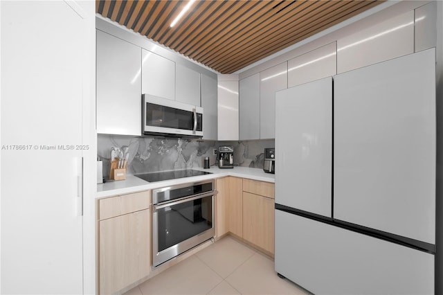 kitchen featuring black electric stovetop, oven, light countertops, and white refrigerator